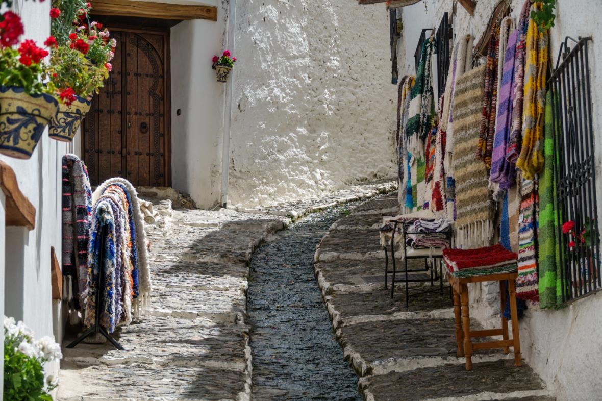 Calle empedrada de un pueblo blanco de la Alpujarra granadina con telares
